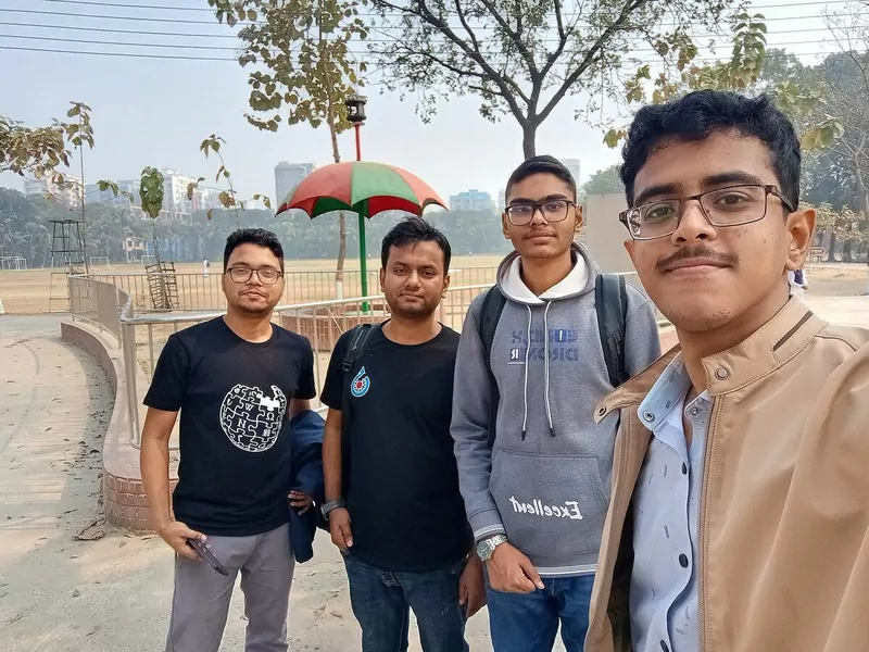 Four Wikimedia volunteers smiling for a selfie outdoors at a college campus in Dhaka