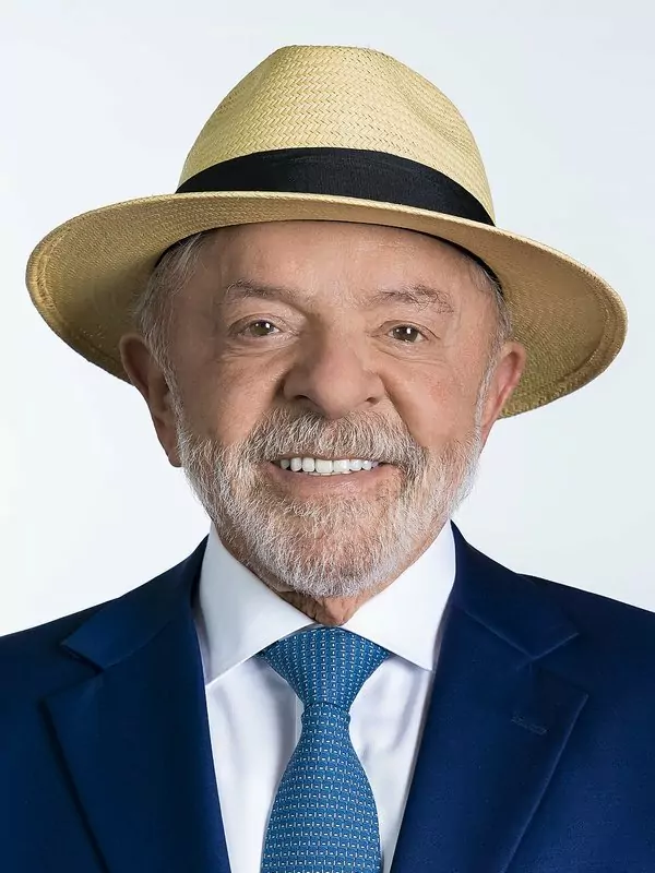 Lula, a smiling white-bearded man in a straw hat, navy suit and blue tie