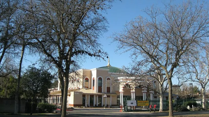 The SALAM Center in Sacramento, a cream-colored building with arches and a green dome, seen through bare trees