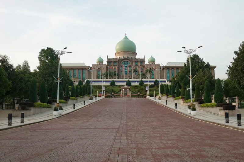 The green-domed Perdana Putra complex at the end of a wide red-brick avenue lined with white lamp posts, clipped conifers and hedges