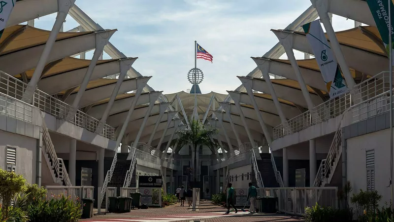 The white tented roofs and diagonal supports of the main grandstand at Sepang International Circuit, with the Malaysian flag flying above a globe-topped tower