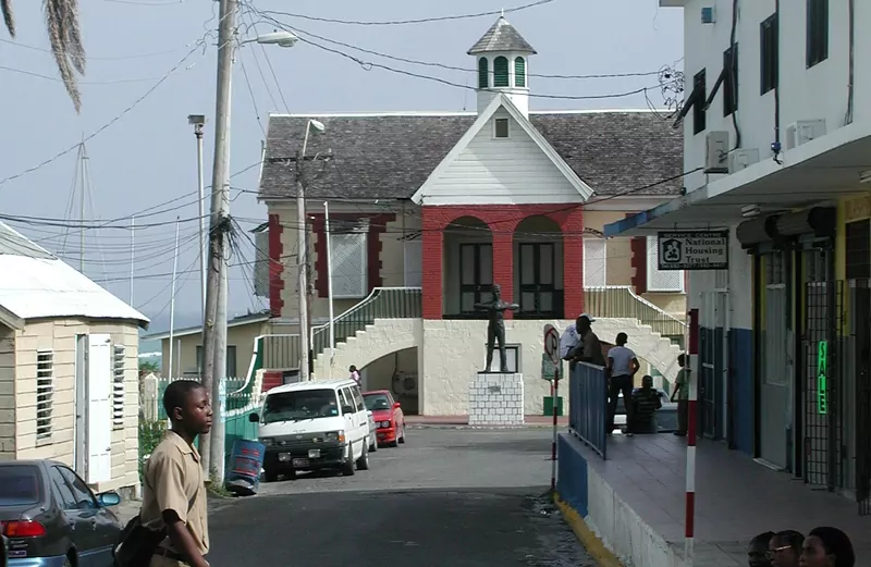 A street leading to the red and cream Morant Bay courthouse with a bronze statue of Paul Bogle on a white plinth in front of it