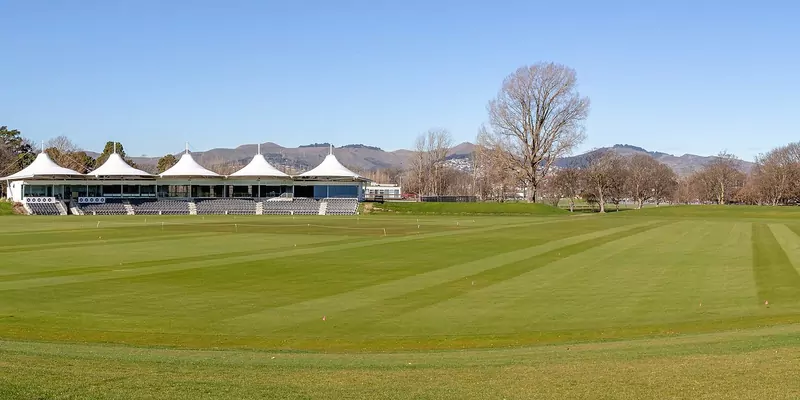 Hagley Oval in Christchurch on a clear day, with a white-roofed pavilion, a striped outfield and hills in the distance