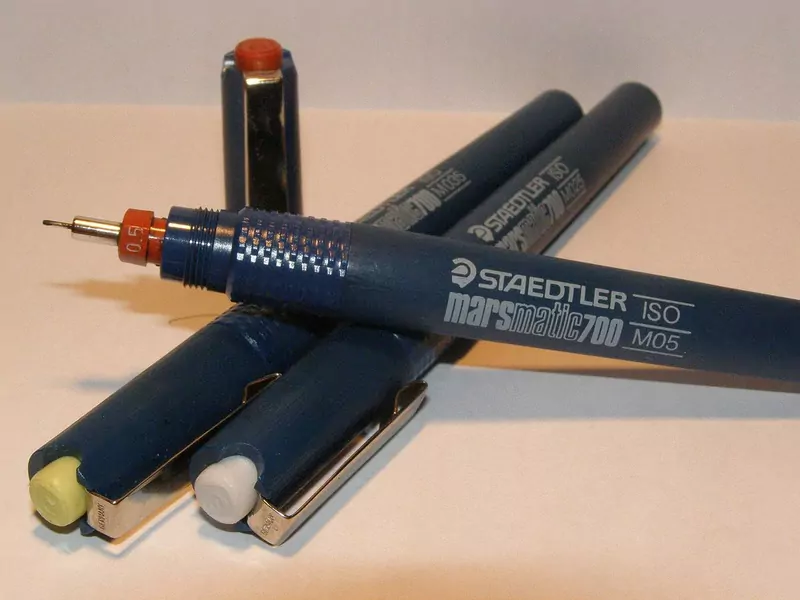 Several dark blue Staedtler technical drawing pens lying on a table