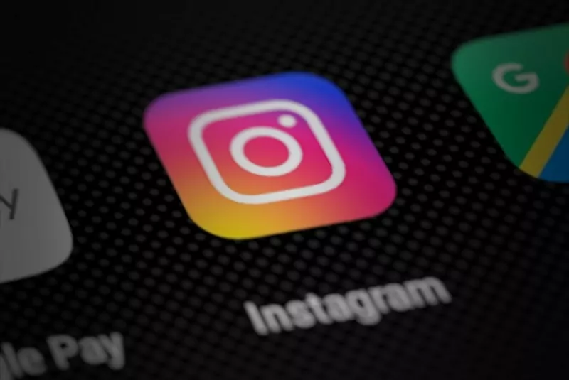 The pink, orange and purple Instagram app icon on a dark phone screen, with parts of two other app icons beside it