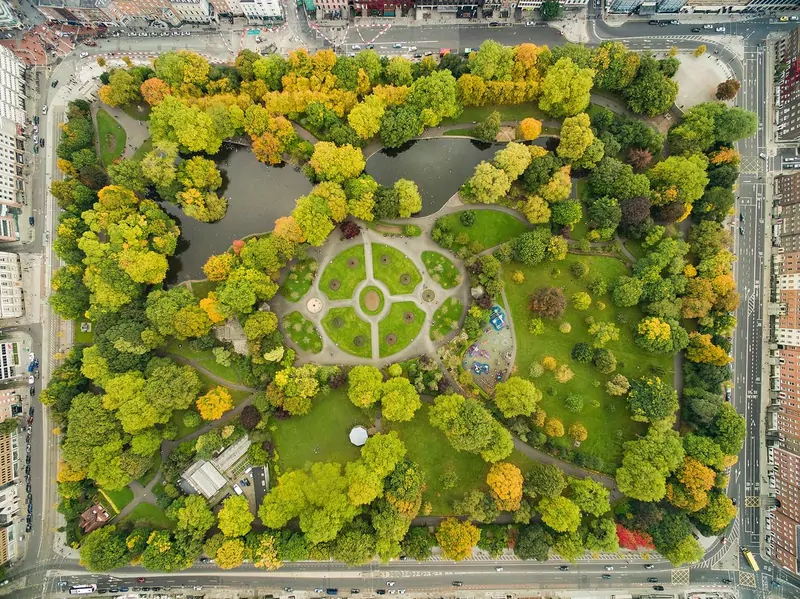 Aerial view of St Stephen's Green park in central Dublin, with yellow and green autumn trees around a pond and a circular garden