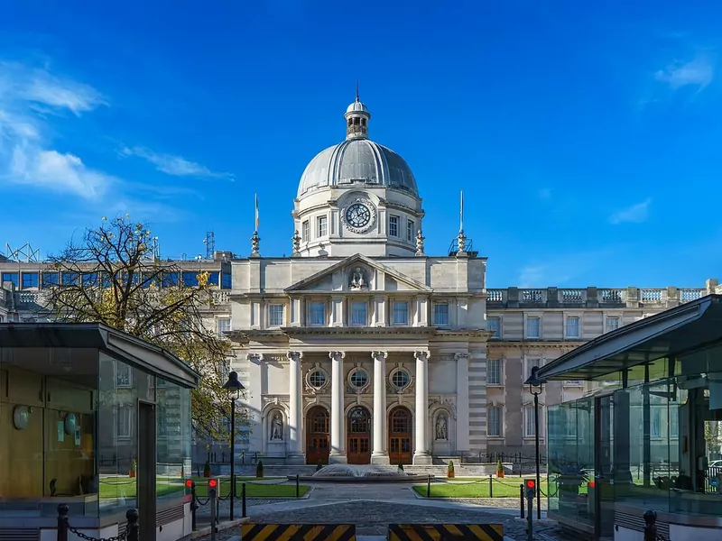 The domed Government Buildings on Merrion Street in Dublin, a pale stone Edwardian building with columns and a clock, under a blue sky