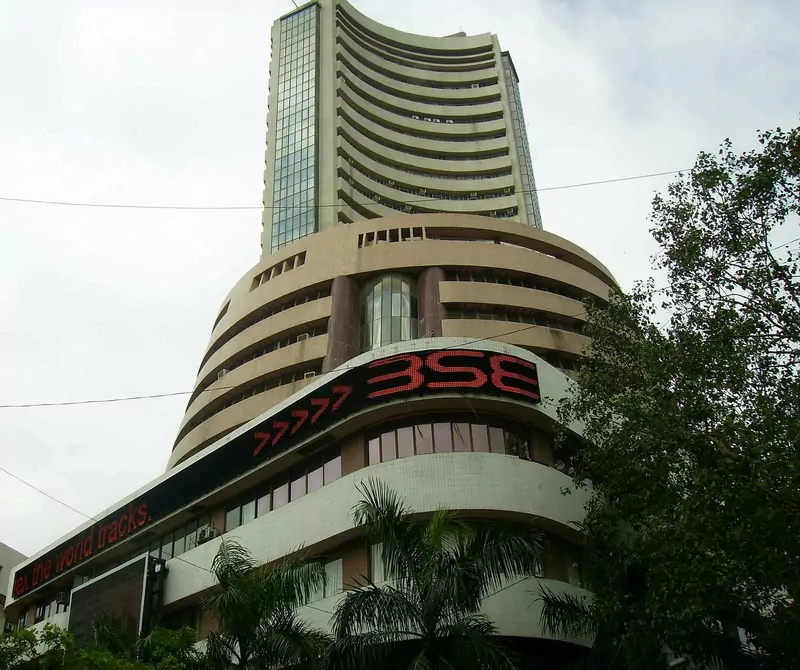 The curved glass and concrete tower of the Bombay Stock Exchange in Mumbai with a red LED board reading BSE