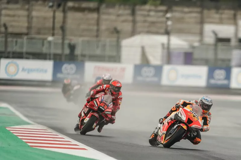 Pol Espargar&oacute; on a Repsol Honda leans through a wet corner at Mandalika with Francesco Bagnaia's red Ducati close behind and spray rising from the damp track