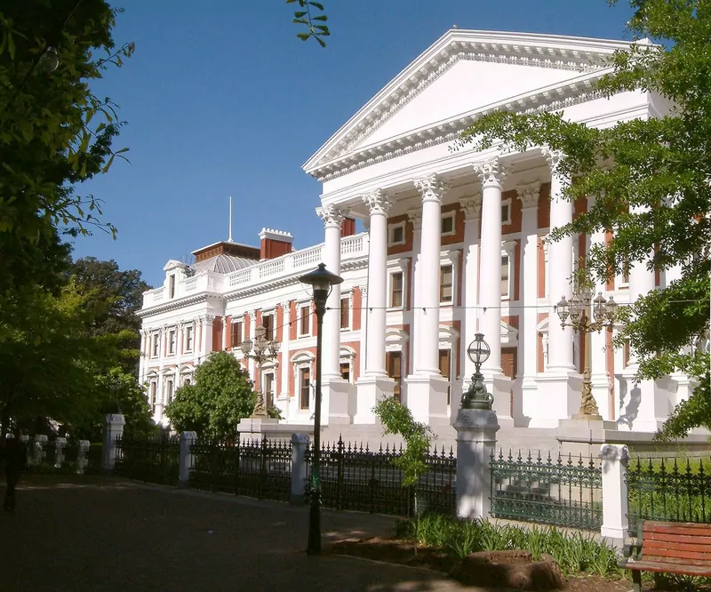The Houses of Parliament in Cape Town seen from a tree-lined street, with a lamp post in front