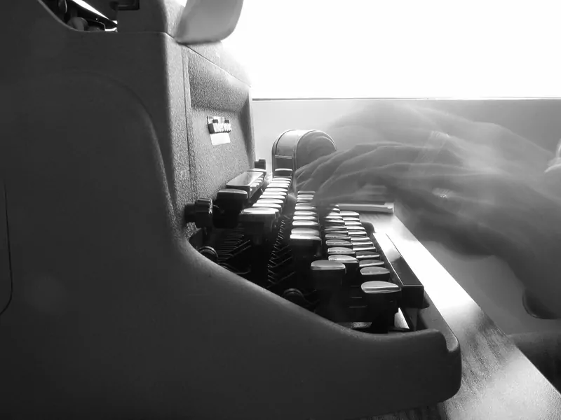 Black-and-white photo of hands typing on an old manual typewriter