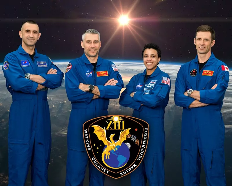 Official Crew-13 portrait: four crew members in blue flight suits with arms crossed, Earth seen from orbit behind them and the mission patch below