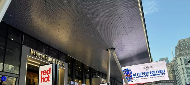 The glass and steel Seventh Avenue entrance to Madison Square Garden under a large overhanging roof, with big screens
