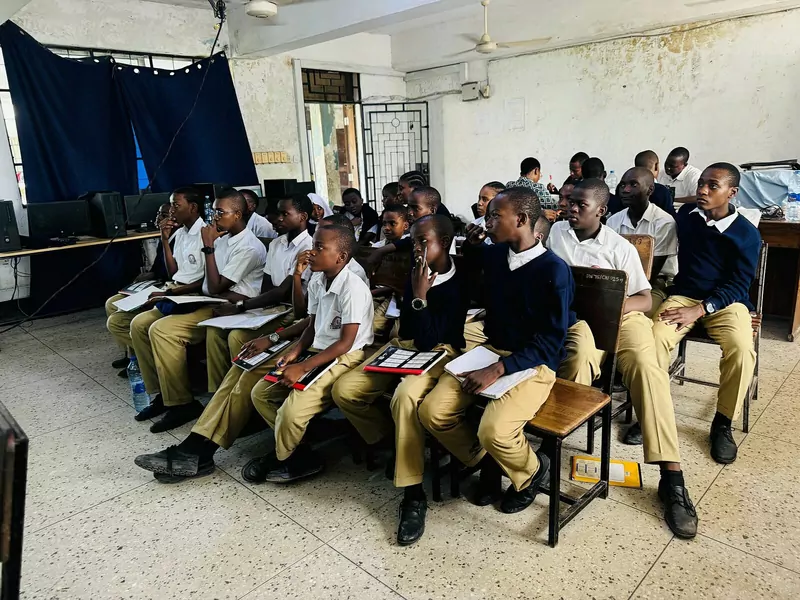 Secondary school students in white shirts and navy sweaters seated in rows in a classroom in Tanzania