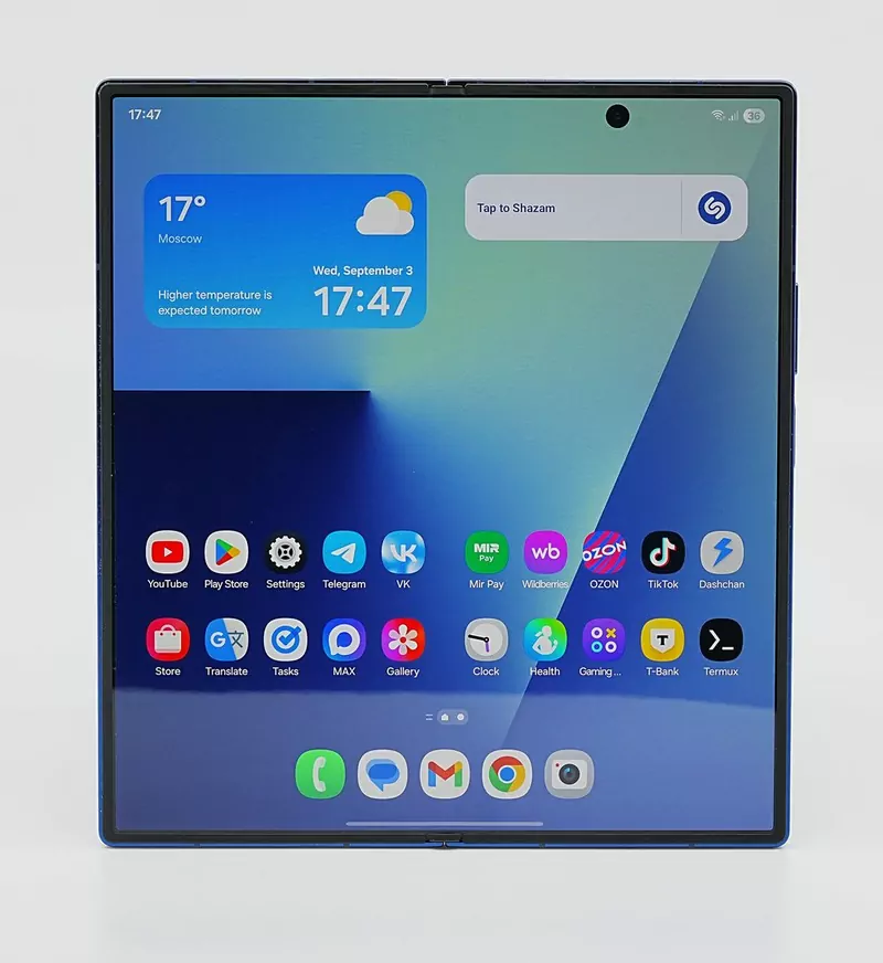 A Samsung Galaxy Z Fold7 opened flat, showing its home screen with a weather widget and rows of app icons