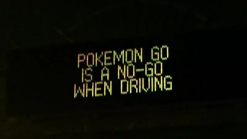 A lit roadside message sign at night reading Pokemon Go is a no-go when driving