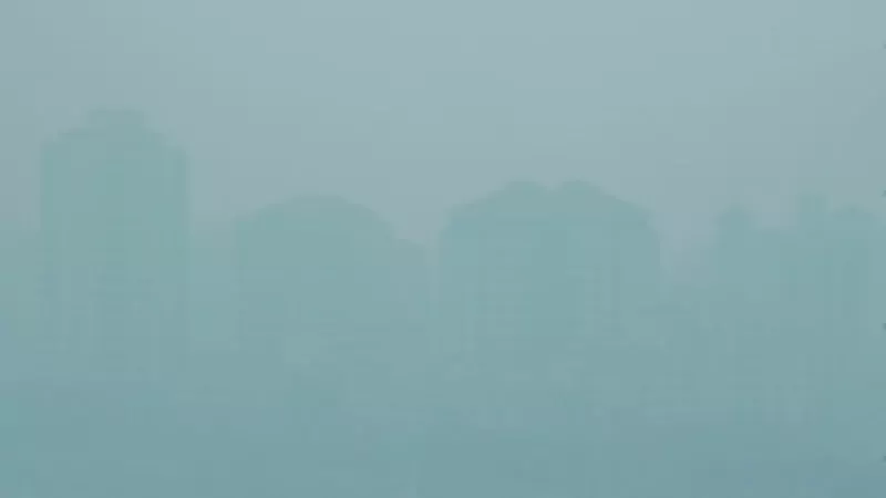 Thick blue-grey haze almost hides the outlines of several tall apartment blocks in Singapore