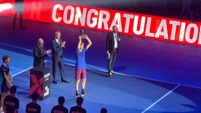 Jannik Sinner lifting a trophy on a stage under a large Congratulations sign