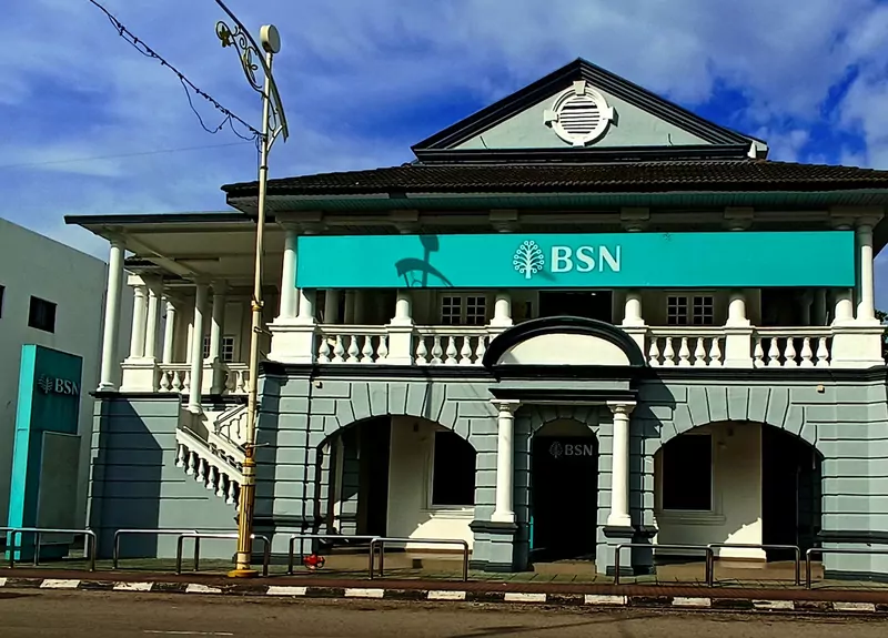 A two-storey Bank Simpanan Nasional branch with white columns, a pediment and a teal BSN signboard