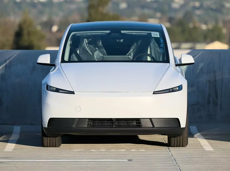 A white Tesla Model Y seen from the front on the top level of a parking garage