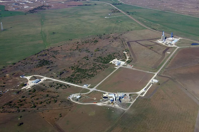 An aerial view of a rocket test site with test stands, roads and a few buildings in green and brown Texas farmland