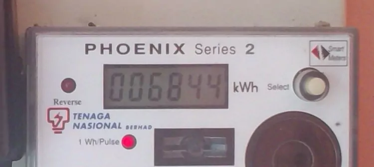 A white Tenaga Nasional Berhad electricity meter, a Phoenix Series 2, with a digital display reading 006844 kWh, a red indicator light and a round black cover