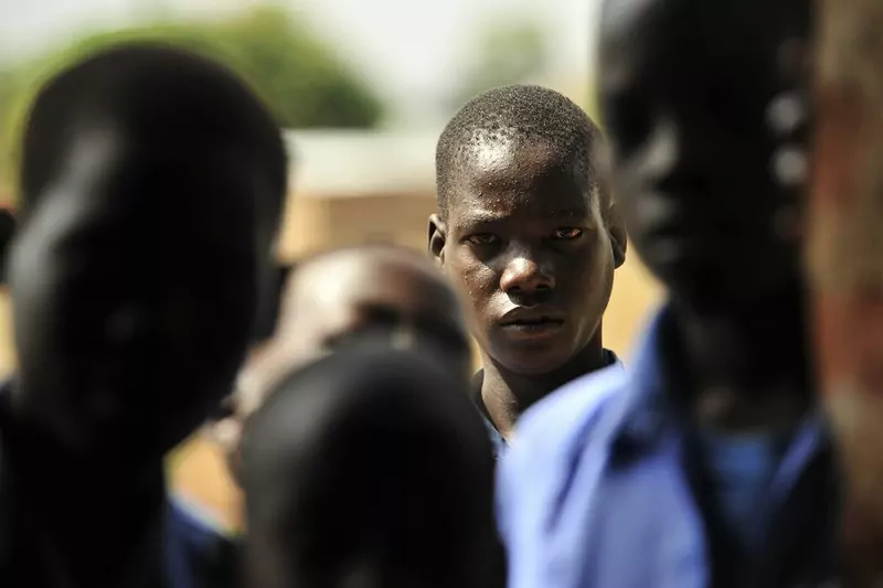 A student in a blue shirt looking into a classroom, with other students in the foreground