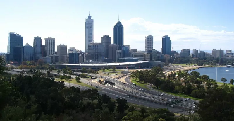 Perth's city-centre towers seen from Kings Park, above a freeway interchange, with the Swan River on the right