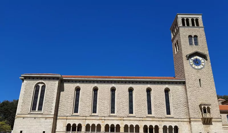 The pale stone Winthrop Hall with tall arched windows and a clock tower against a deep blue sky