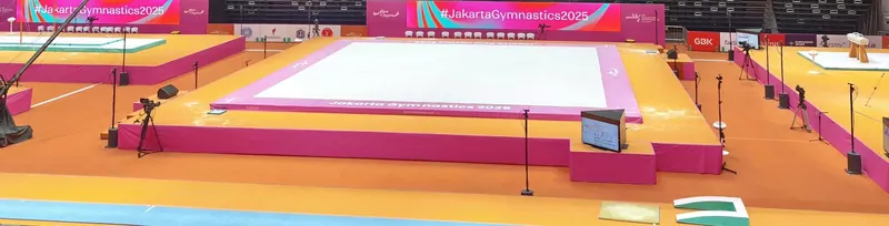 The competition floor and apparatus platforms in an empty arena before a World Championships session, with pink and orange podiums, a floor exercise mat and a pommel horse