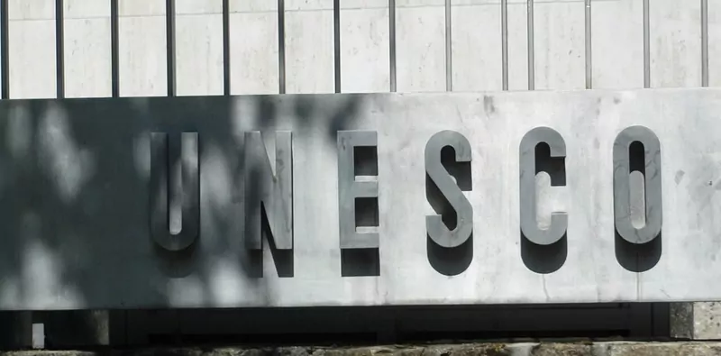 Metal letters spelling UNESCO on a stone wall outside the organisation's headquarters